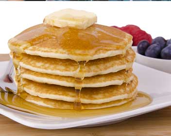 A stack of delicious iHop original buttermilk pancakes topped with butter and syrup.